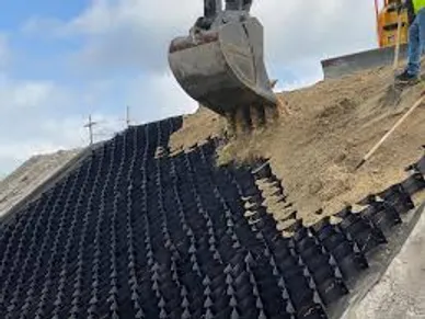 Excavator filling geo-cells with sand on a steep slope
